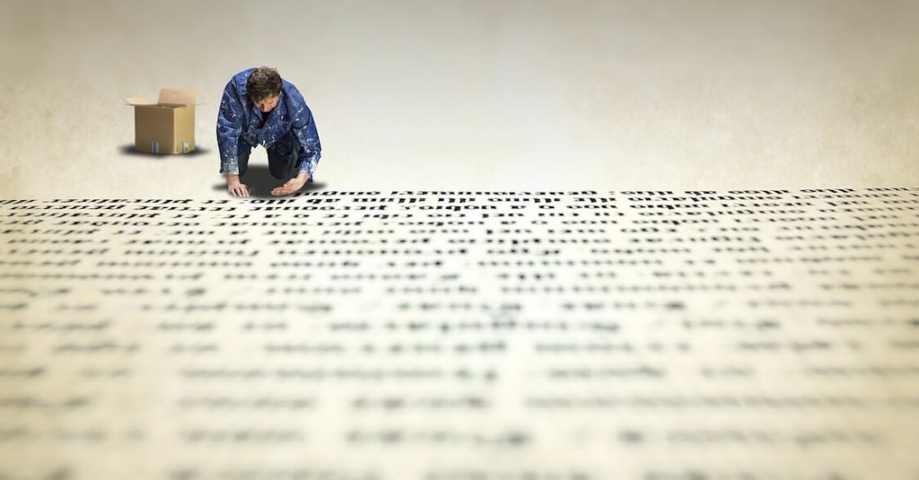 A photo of a man on his knees, writing a long text on the floor.