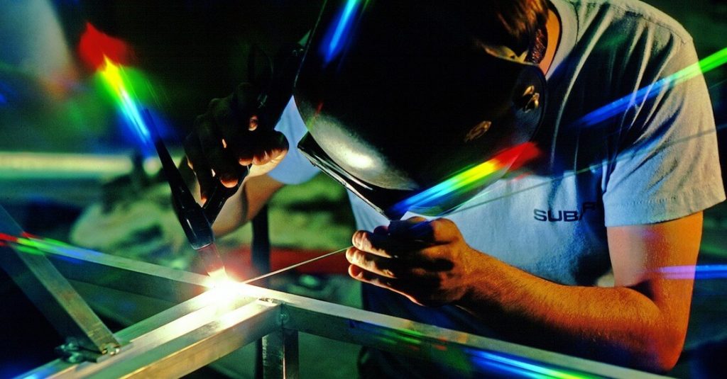 A man in a mask welding iron.